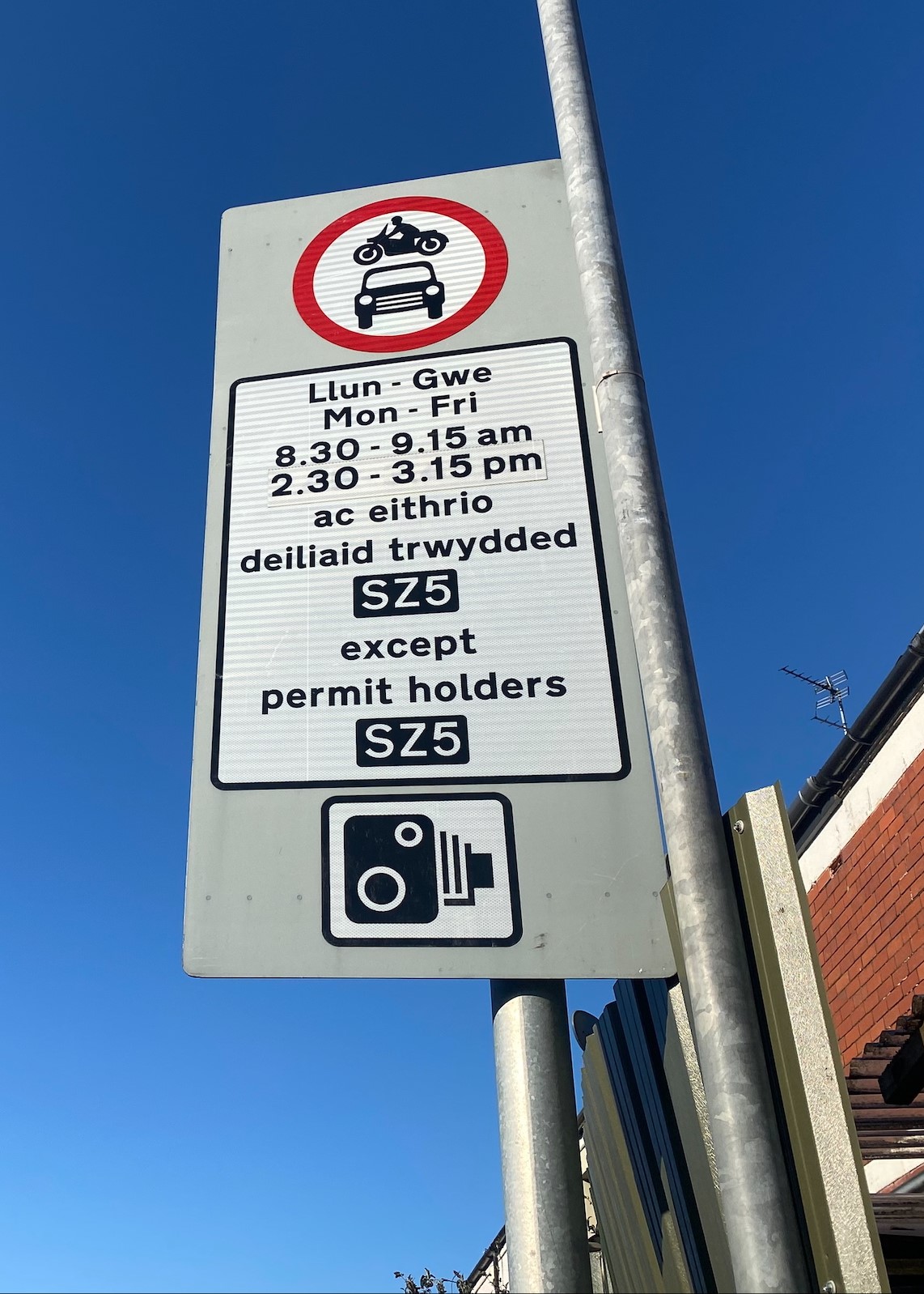 Arwydd stryd ysgol, yn egluro oriau gweithredu, yn datgan bod CCTV ar waith, yn dweud pa dderbynyddion sy'n rhydd o gyfyngiadau, ac yn gwneud yn glir nad yw cerbydau modurol yn cael eu caniatau