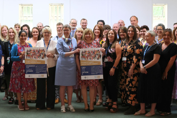 Mae Lynne Neagle MS a staff y rhaglen '111 gwasgwch 2' sy'n dal posteri hysbysebol fel torf.